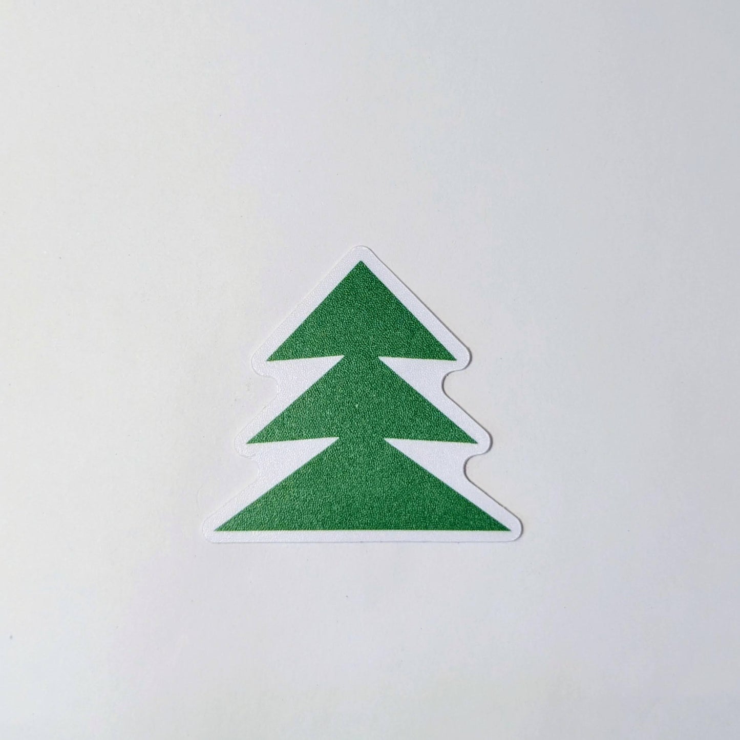Sticker of green tree outlined in white on a white background