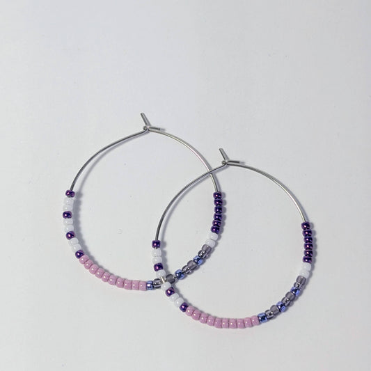 Pair of hoop earrings with beaded accents on a light gray background