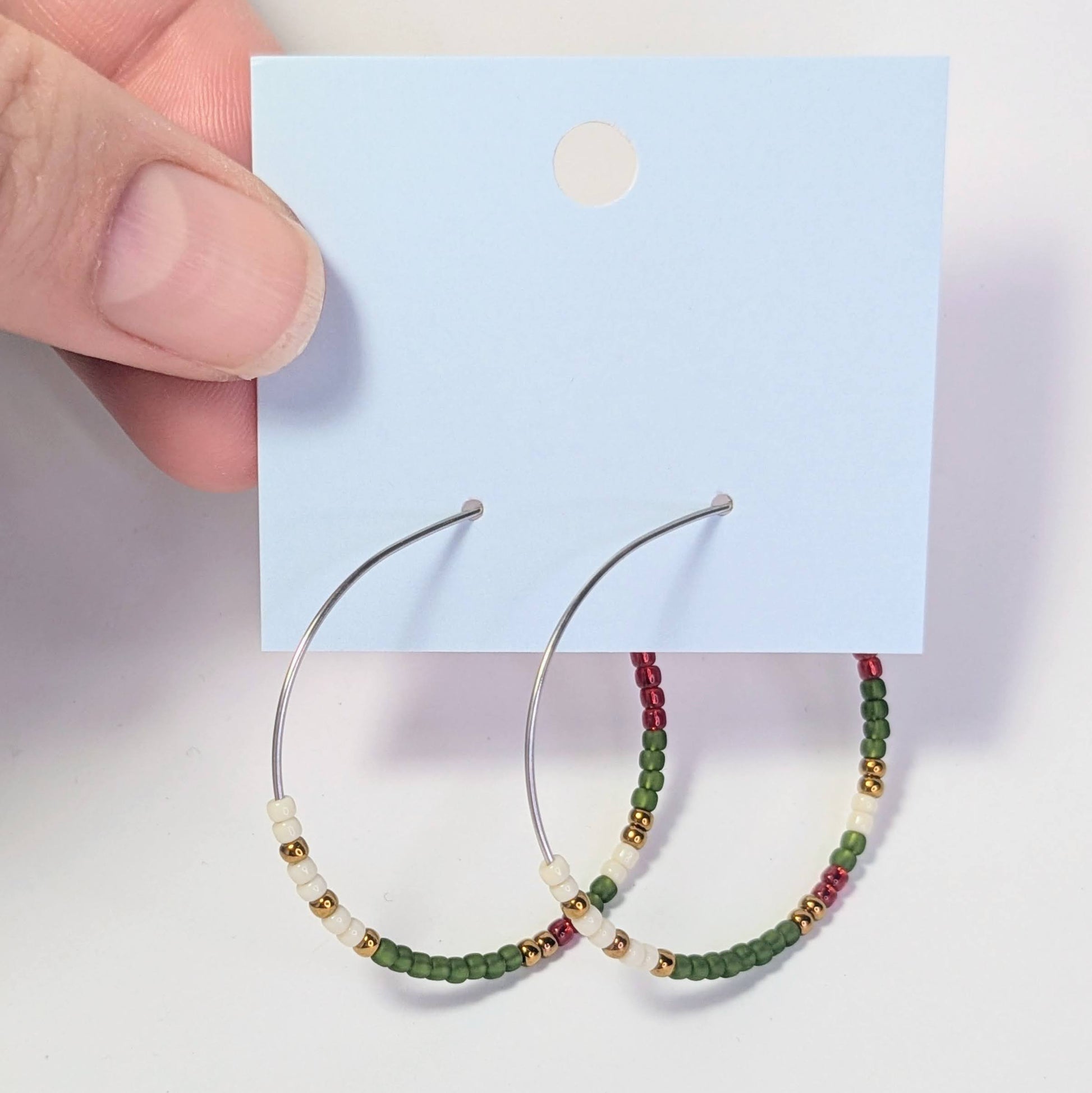 Hoop earrings with bead detailing on a card against a light background