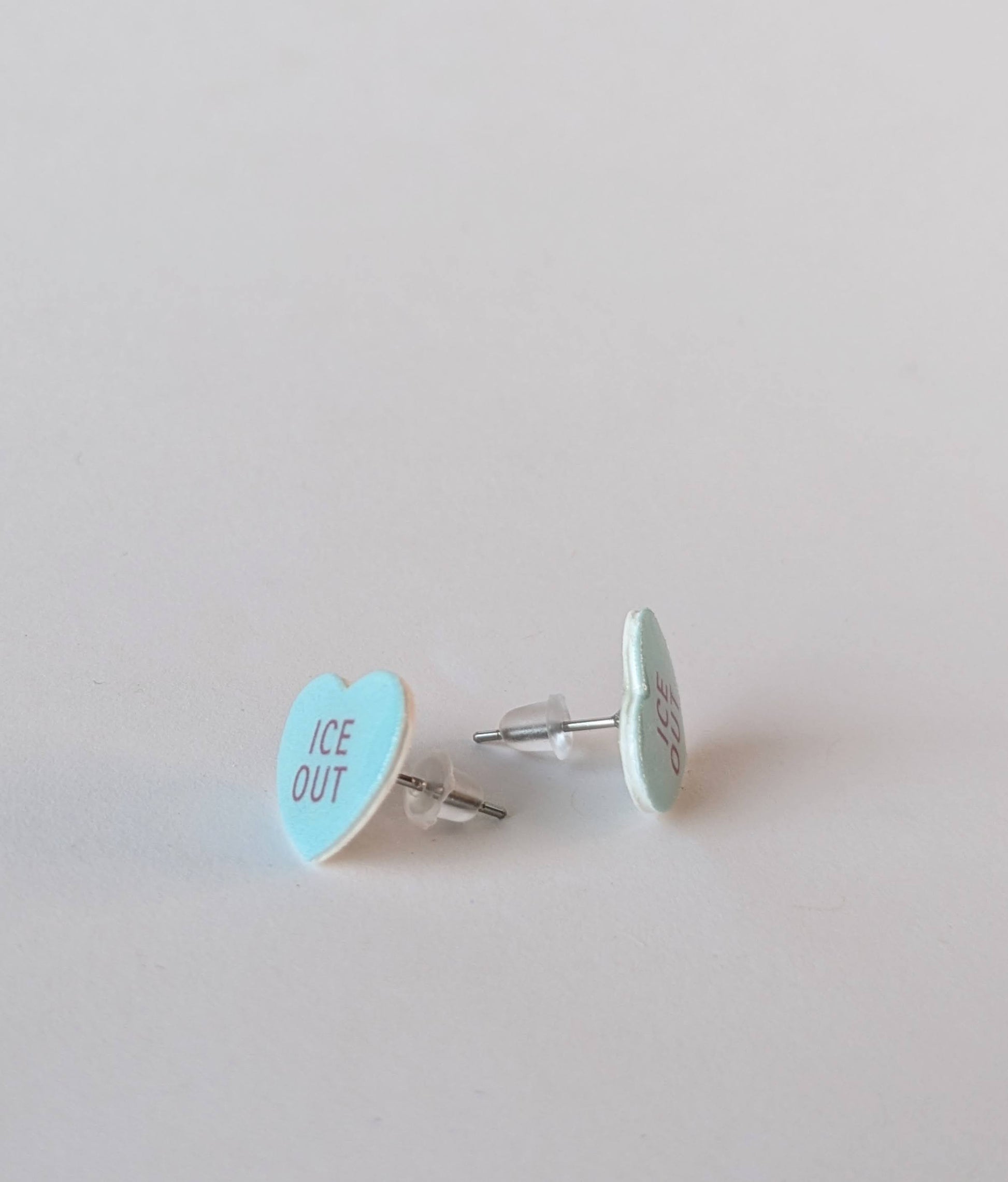 Heart-shaped earrings with 'ICE OUT' text on a light gray background
