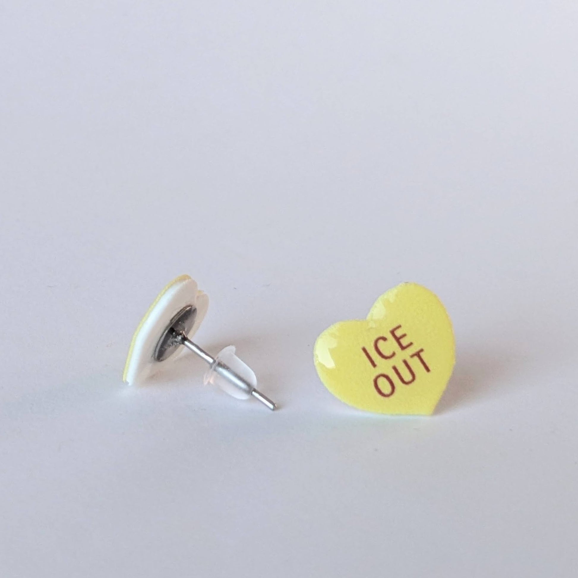 Heart-shaped earrings with 'ICE OUT' text on a light gray background