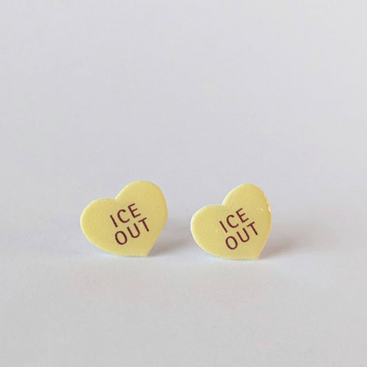 Heart-shaped 'ICE OUT' earrings on a light gray background