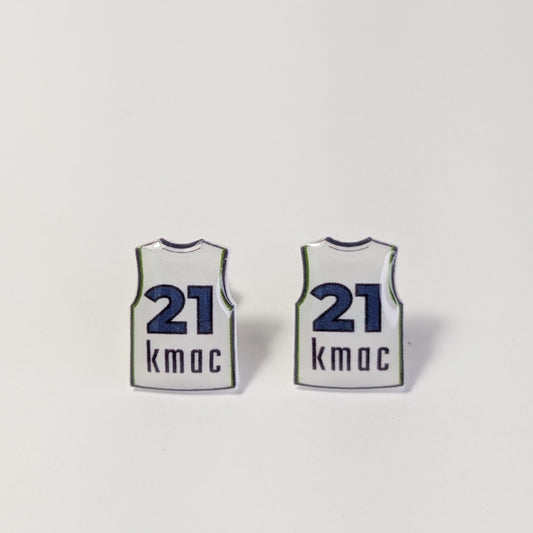Two small earrings shaped like white basketball jerseys with navy blue numbers 21 and the name 'kmac' printed below, shown on a plain light background.