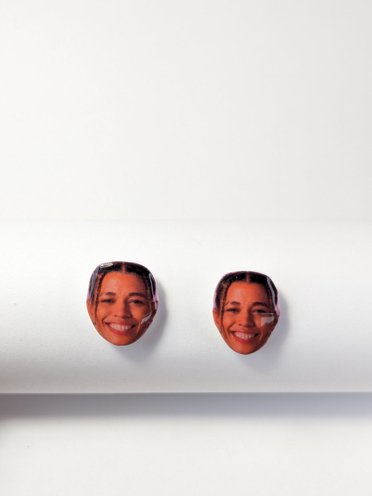 Two stud earrings featuring printed smiling face of Natasha Cloud, displayed on a clean white surface against a white background.