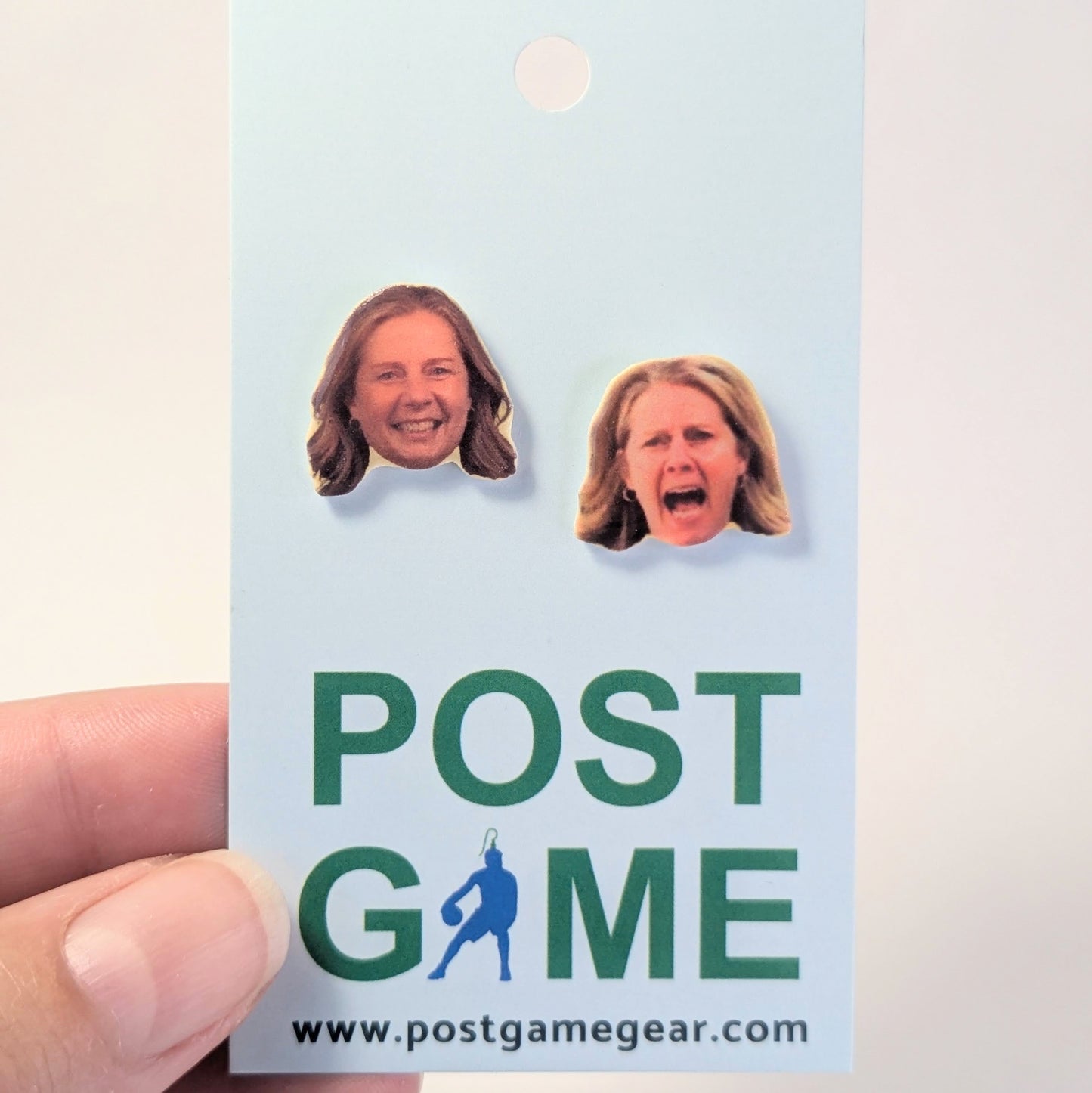 A hand holding a light blue card featuring the fface of a women, with the text 'POST GAME' and 'www.postgamegear'.