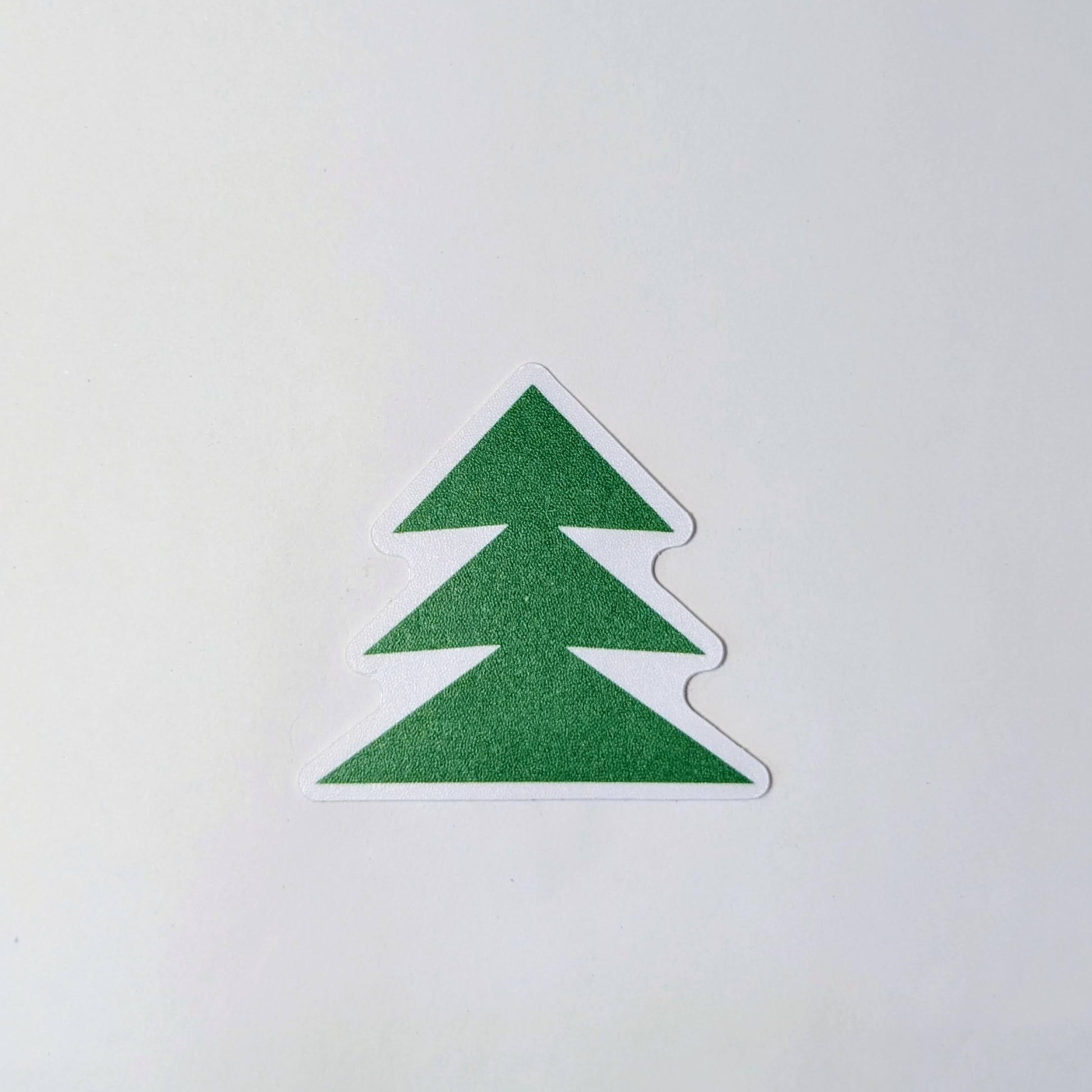 Sticker of green tree outlined in white on a white background