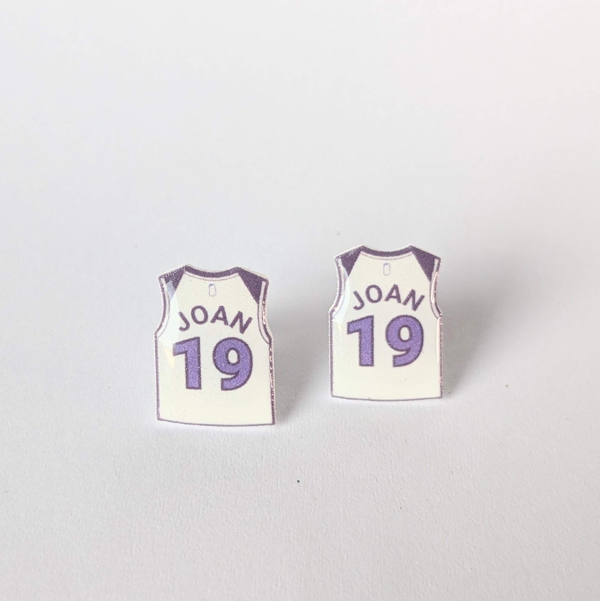 Pair of earrings shaped like basketball jerseys with 'JOAN' and number '19' on a white background