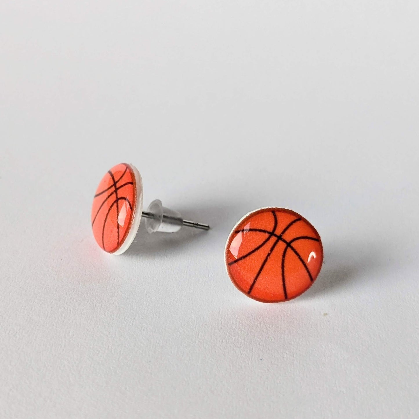 Basketball-themed earrings on a light gray background