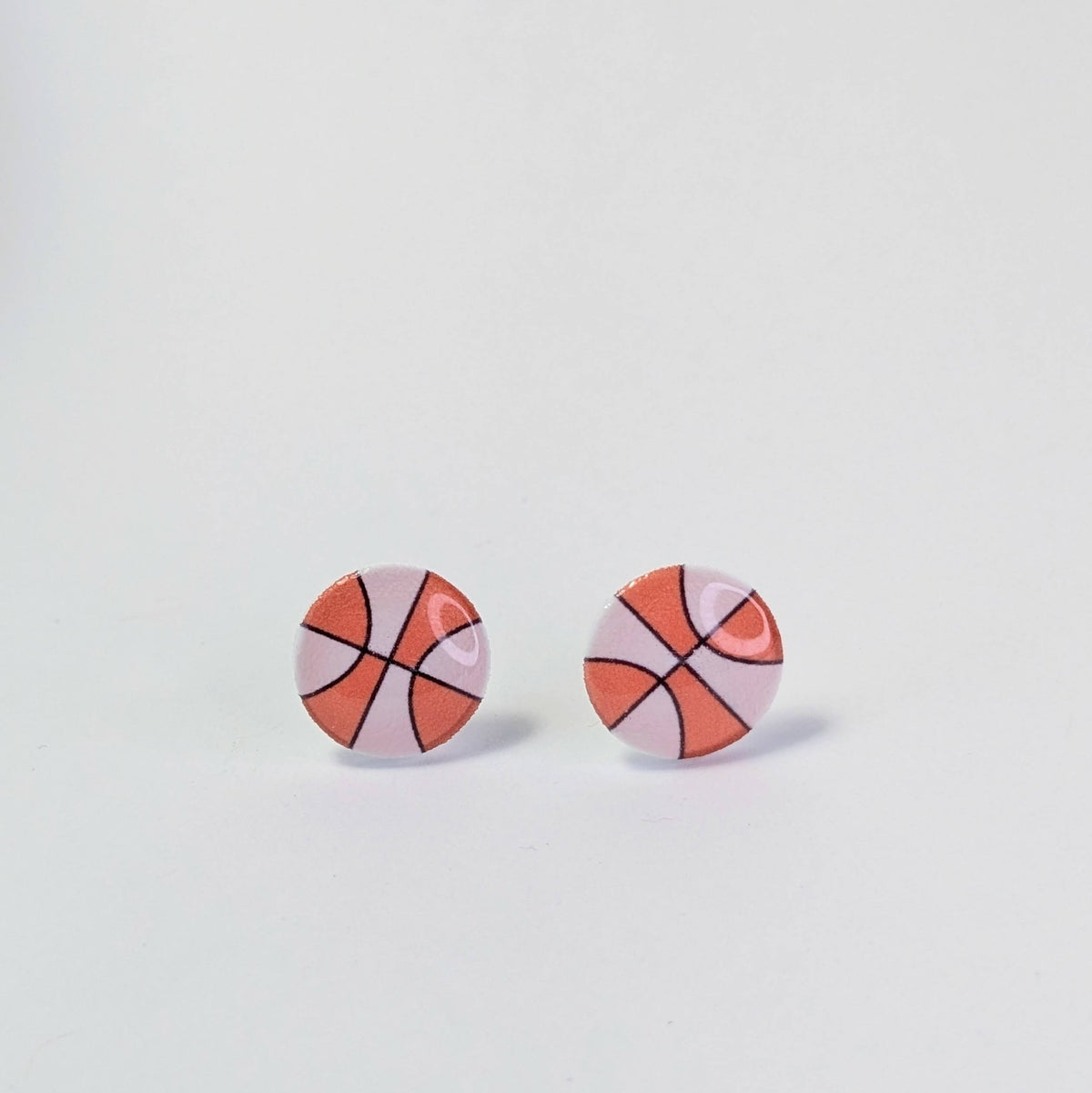 Basketball-shaped earrings on a light gray background