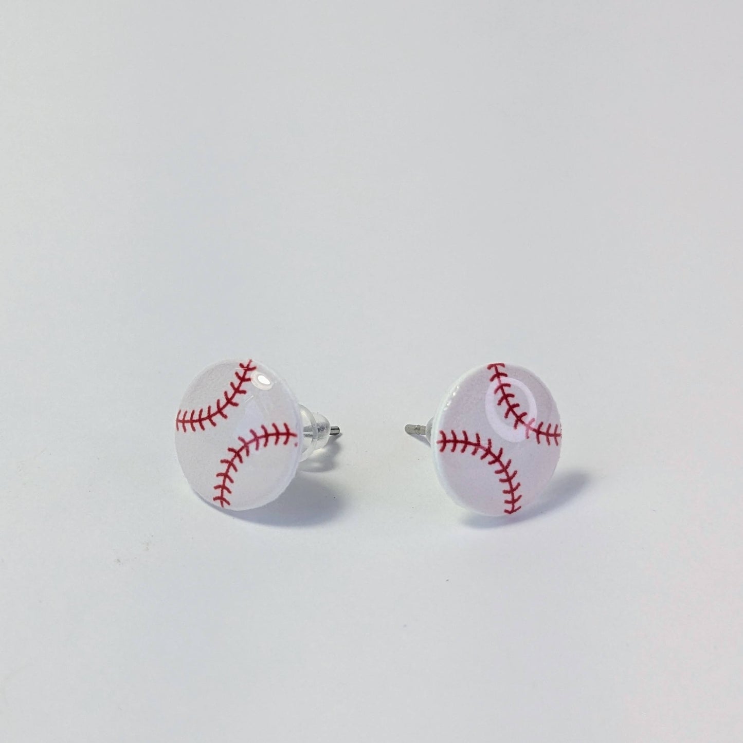 Baseball-shaped earrings on a light gray background