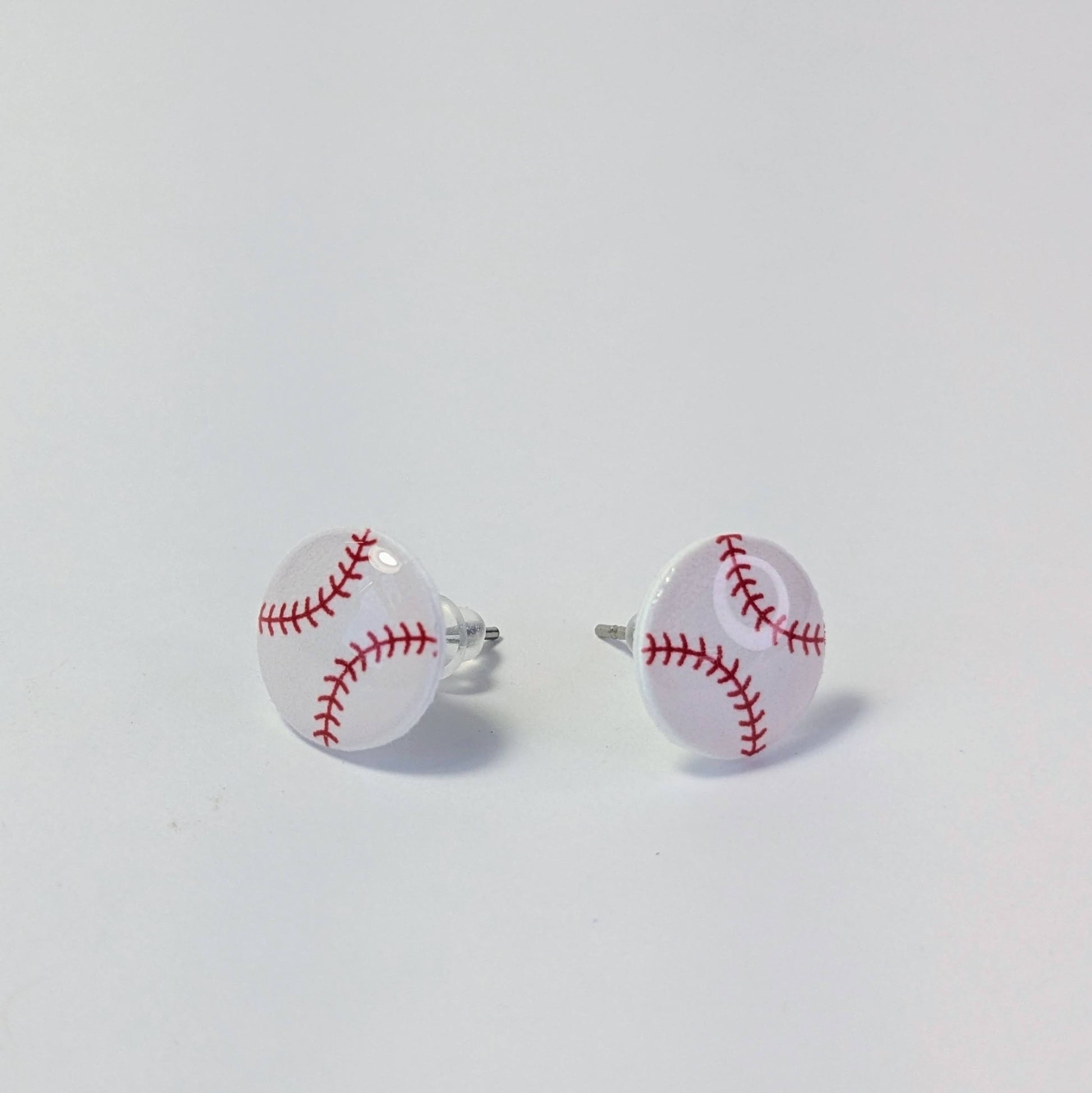 Baseball-shaped earrings on a light gray background