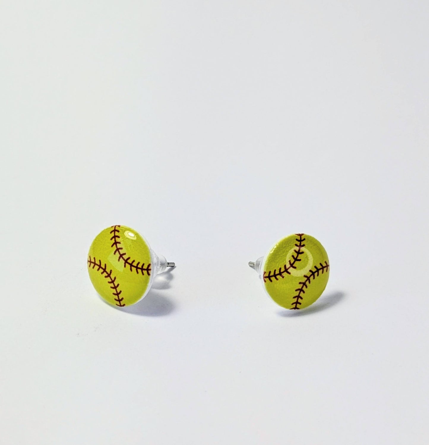 Yellow softball-shaped earrings on a light gray background