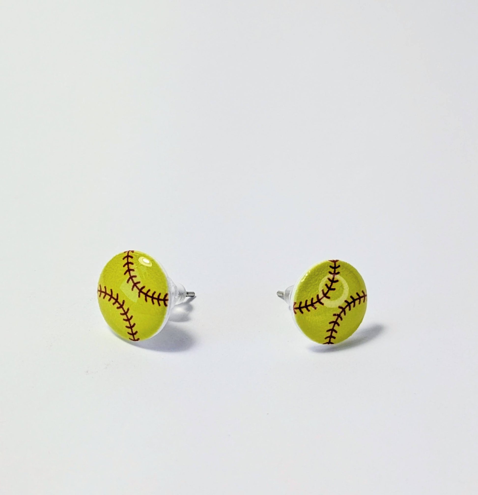 Yellow softball-shaped earrings on a light gray background