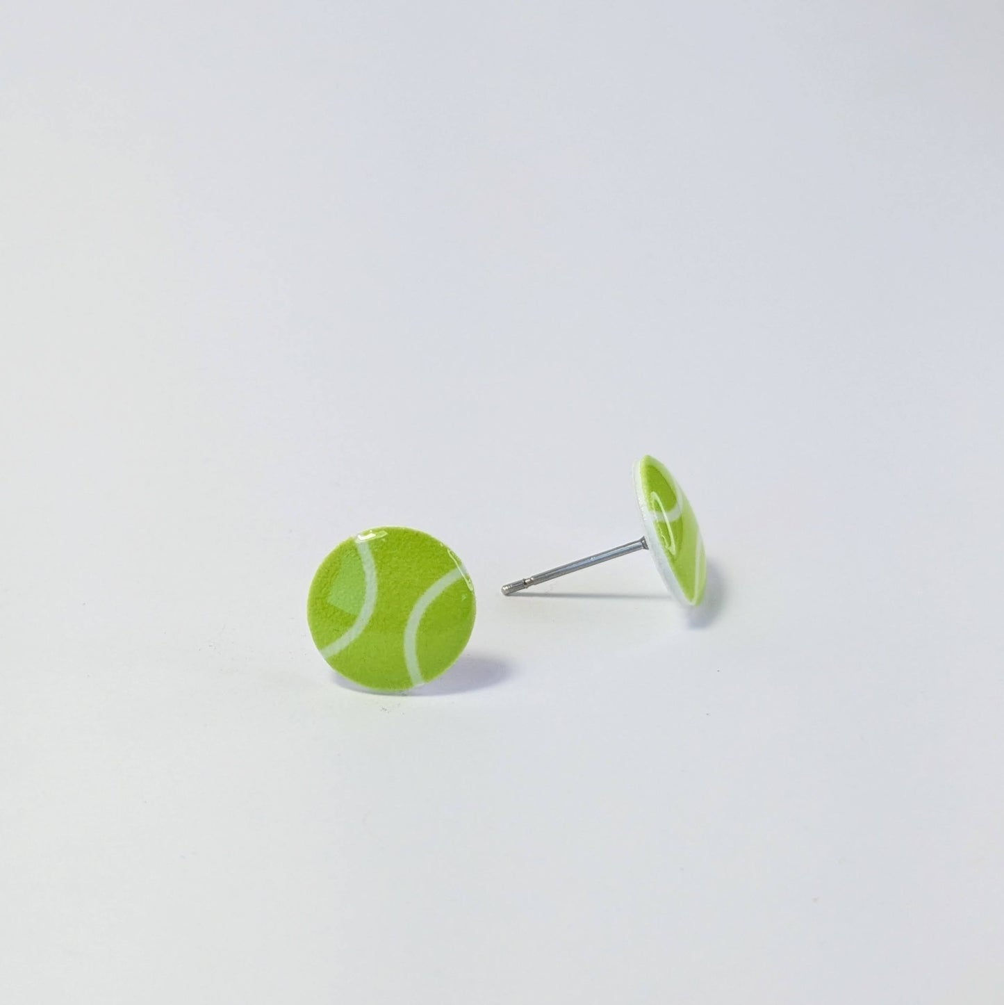 Tennis ball-shaped earrings on a light gray background