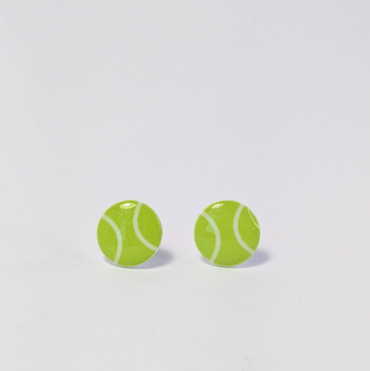 Tennis ball-shaped earrings on a light gray background