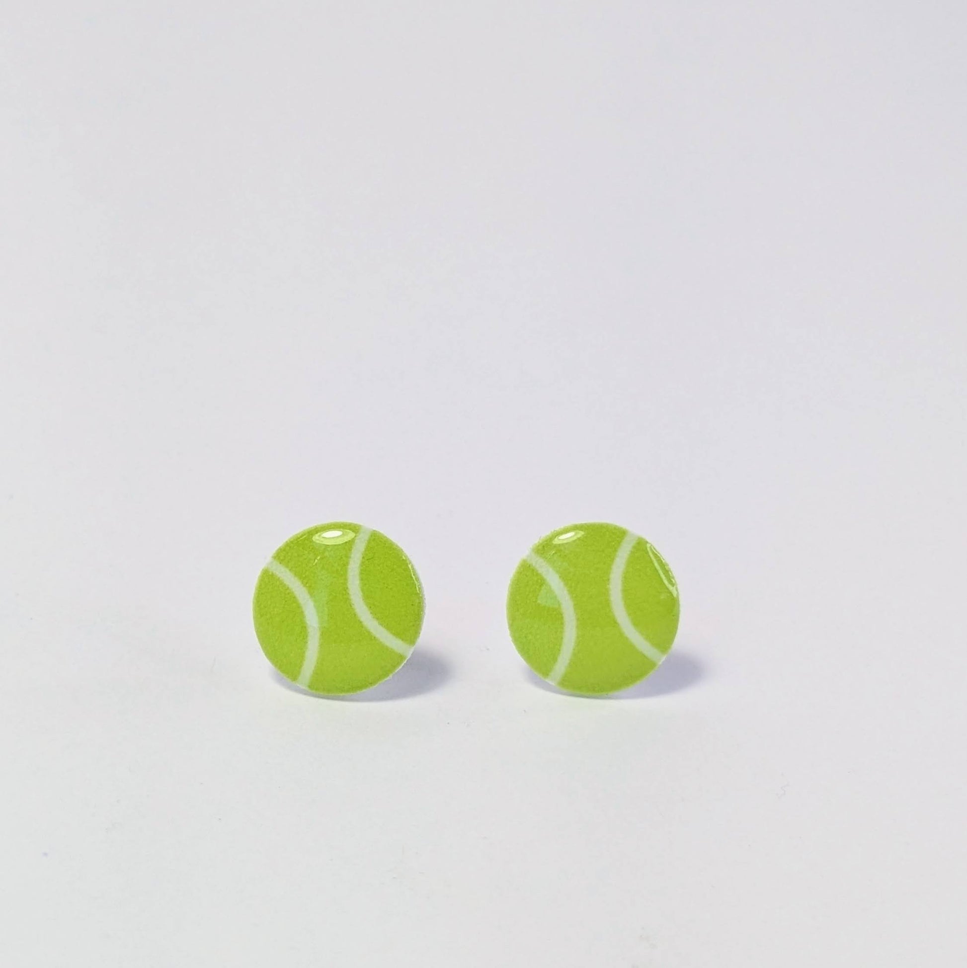 Tennis ball-shaped earrings on a light gray background