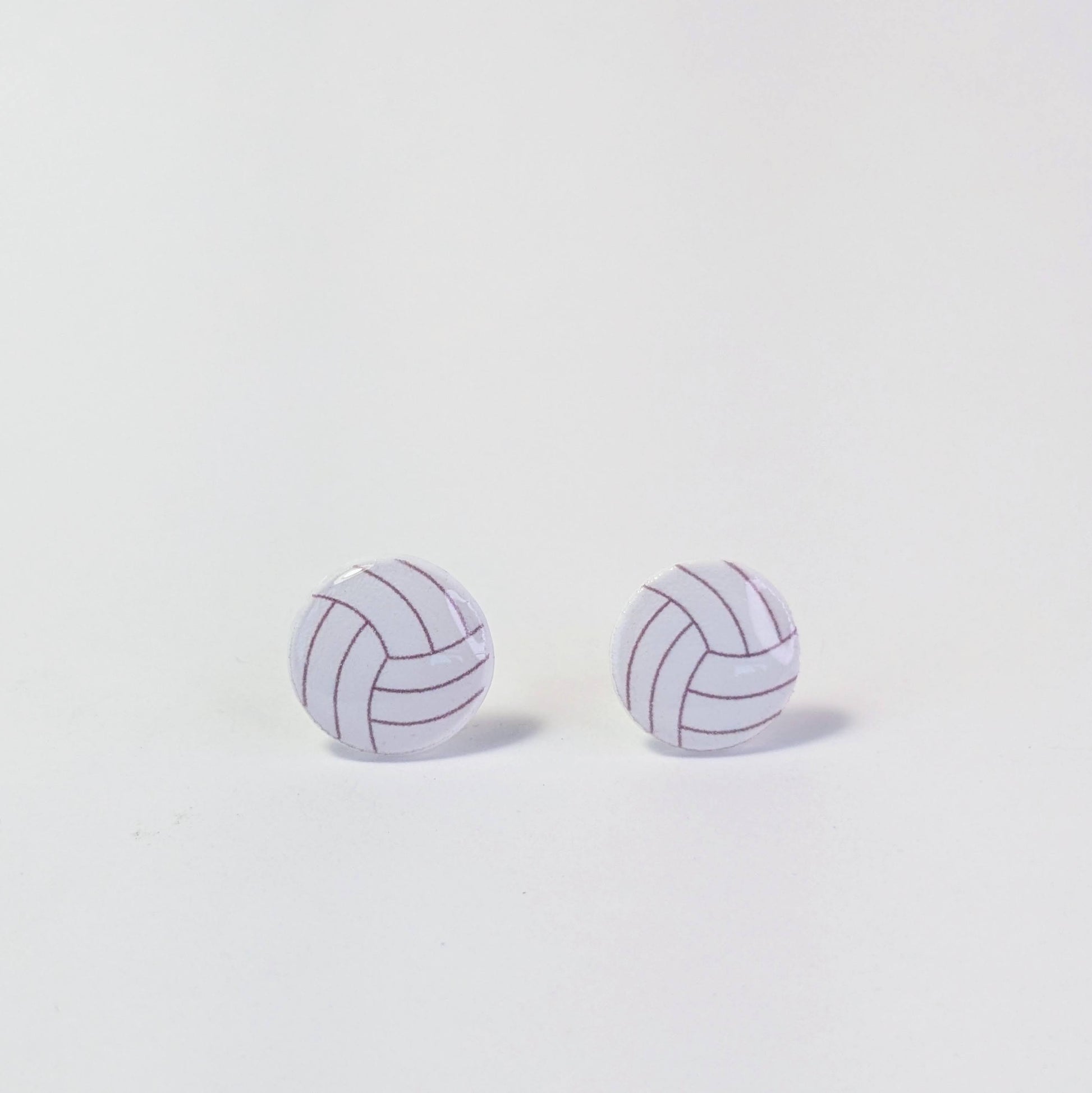 Pair of volleyball-shaped earrings on a light gray background