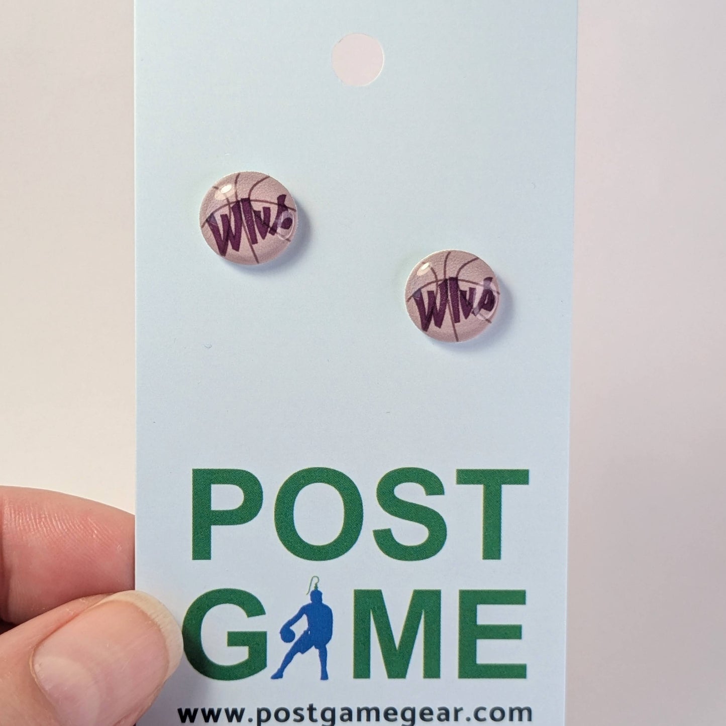 Basketball-themed earrings on a 'POST GAME' branded card held by a hand.