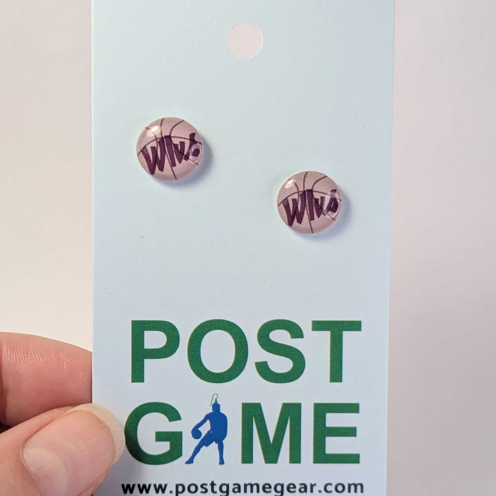 Basketball-themed earrings on a 'POST GAME' branded card held by a hand.