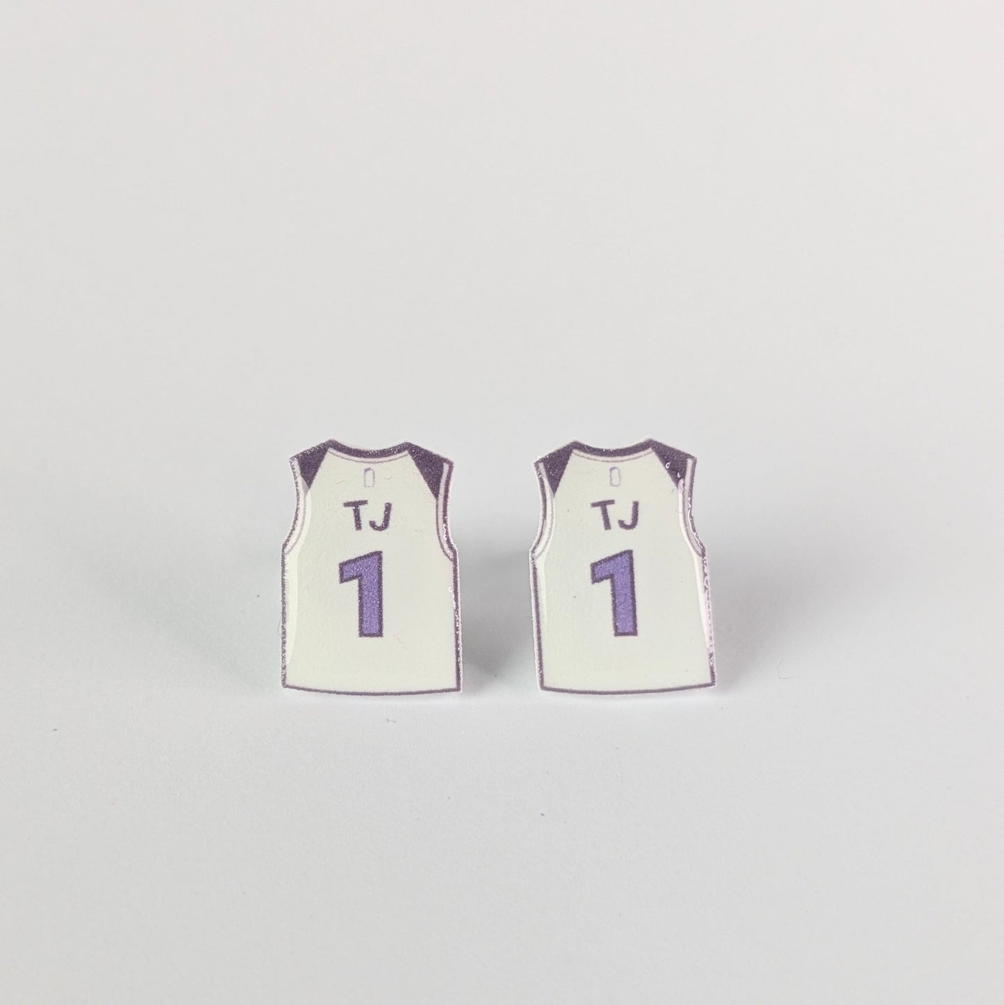Two miniature basketball jerseys with 'TJ' and number '1' on a light gray background