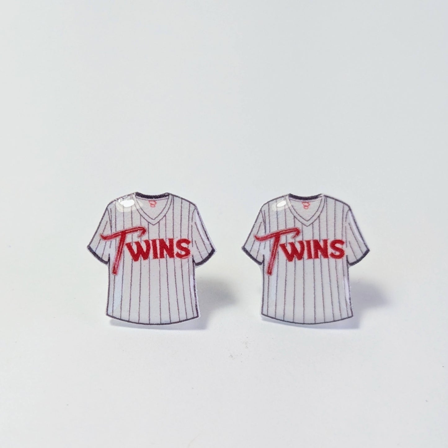 Two miniature baseball jerseys with 'Twins' text on a light gray background