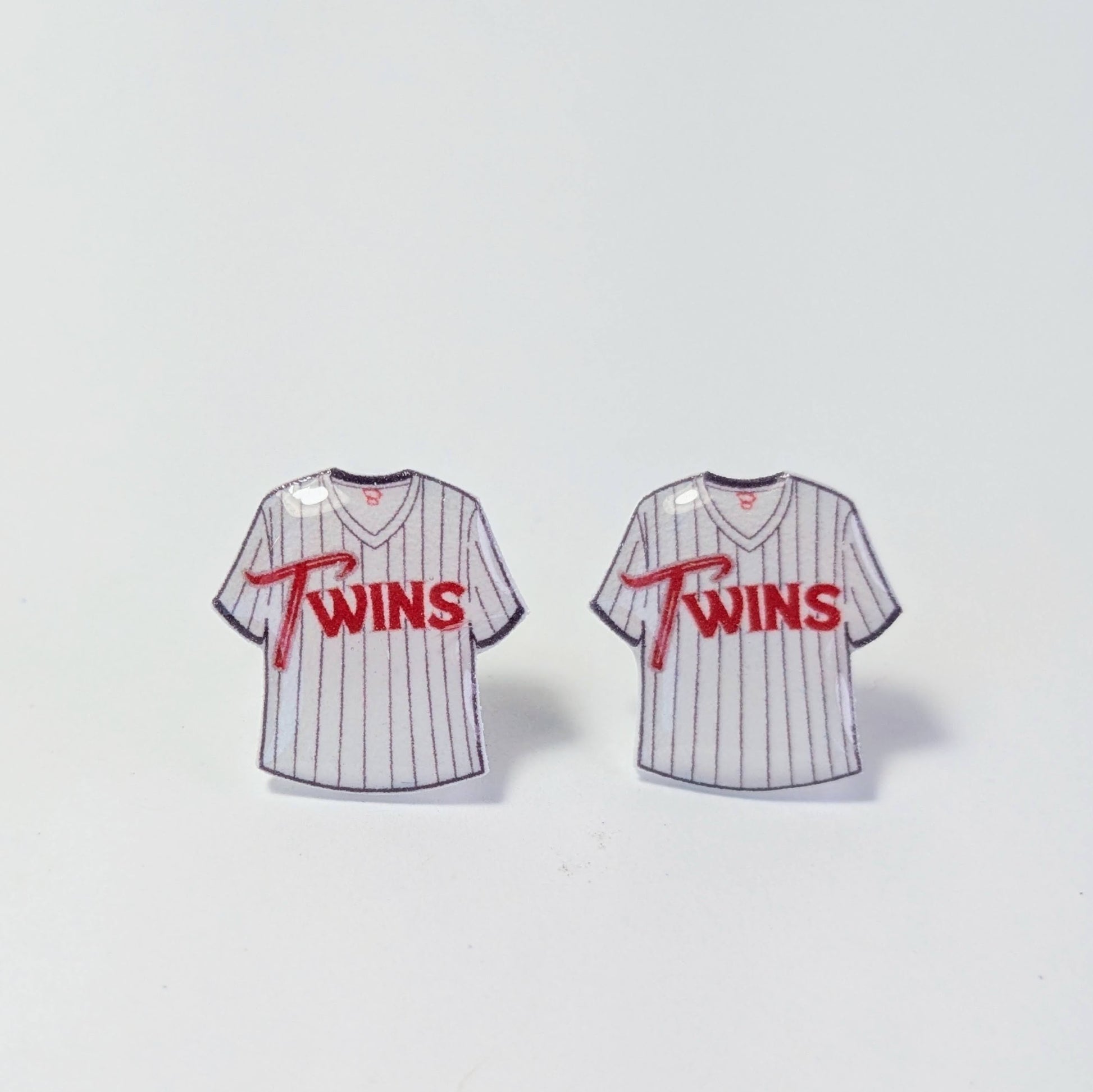 Two miniature baseball jerseys with 'Twins' text on a light gray background