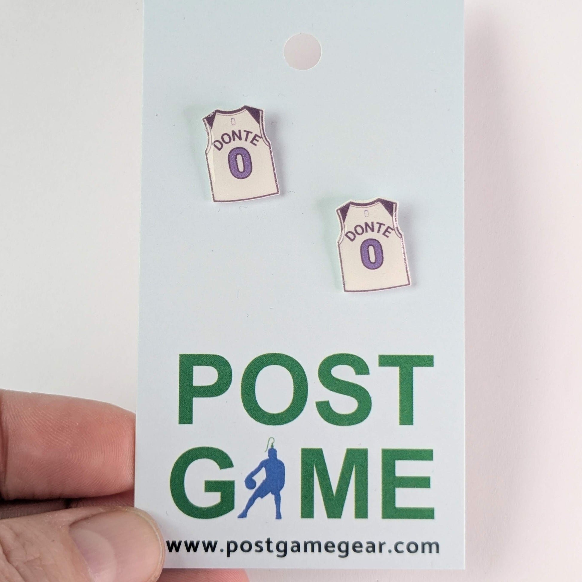 Pair of earrings shaped like basketball jerseys on a 'POST GAME' branded card.