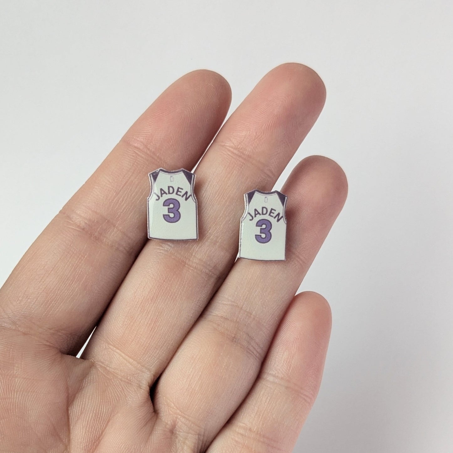 Two small earrings shaped like miniature basketball jerseys with the number 3 and name 'Jaden' on a light background.