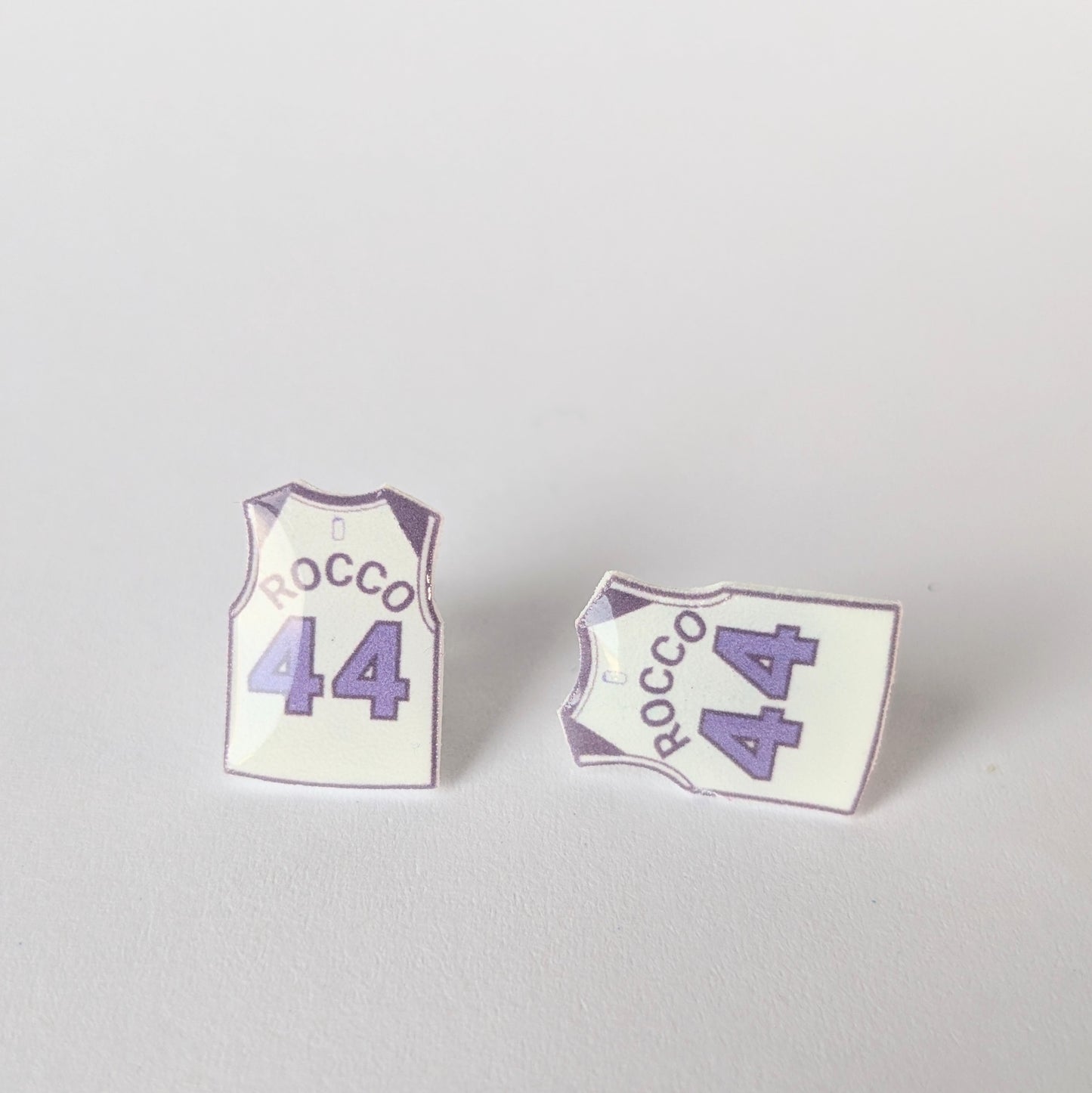 Two earrings shaped like basketball jerseys with 'Rocco 44' text on a light gray background.