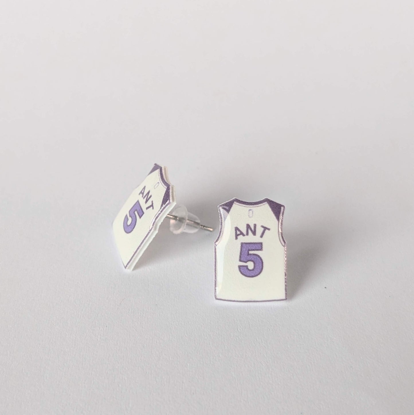 Earrings shaped like miniature basketball jerseys on a gray background