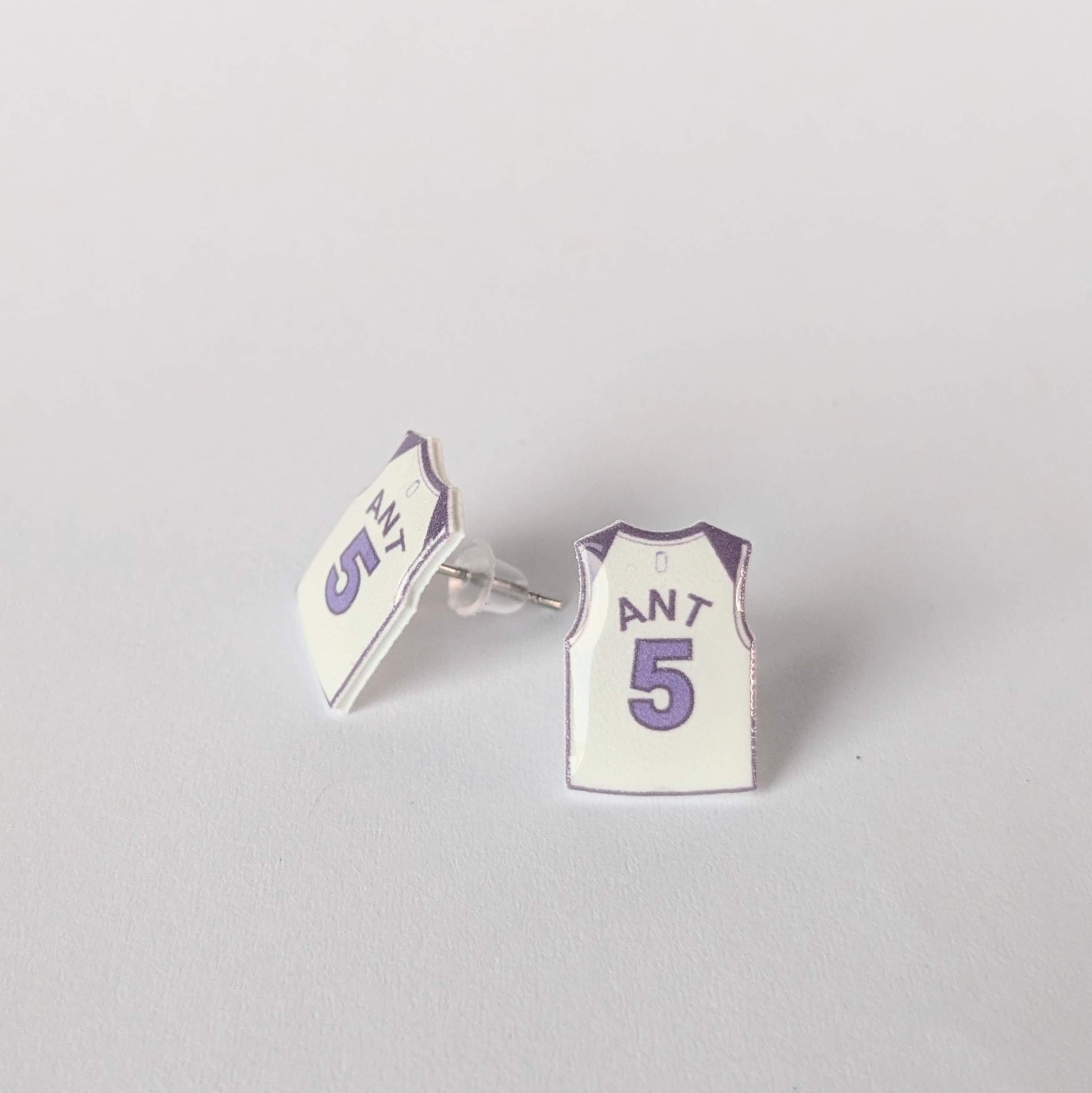 Earrings shaped like miniature basketball jerseys on a gray background