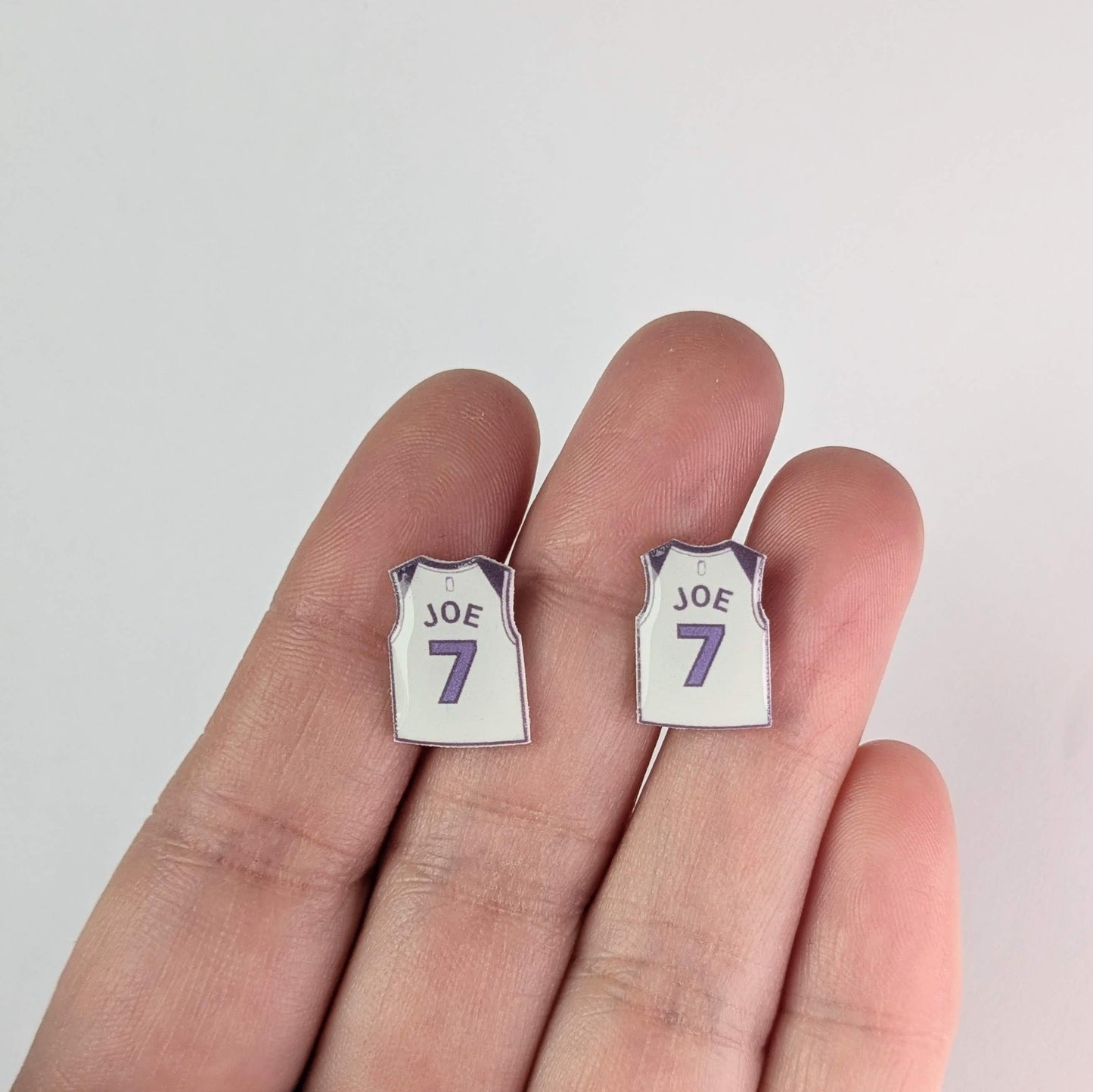 Pair of earrings shaped like miniature sports jerseys with 'JOE' and number '7' on a white background.