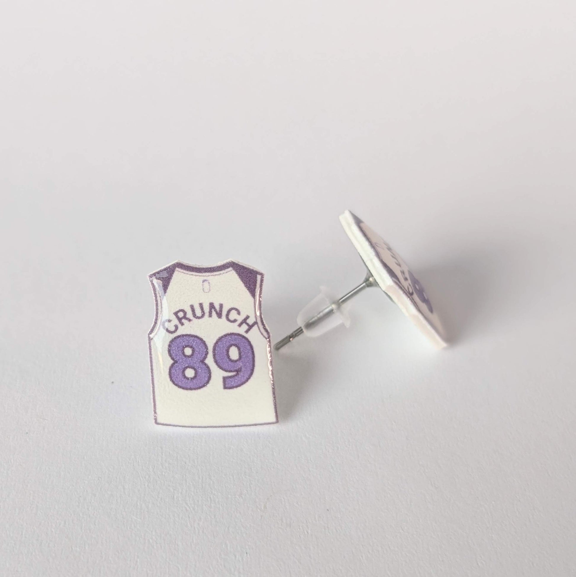 Earring with 'CRUNCH 89' design on a light gray background