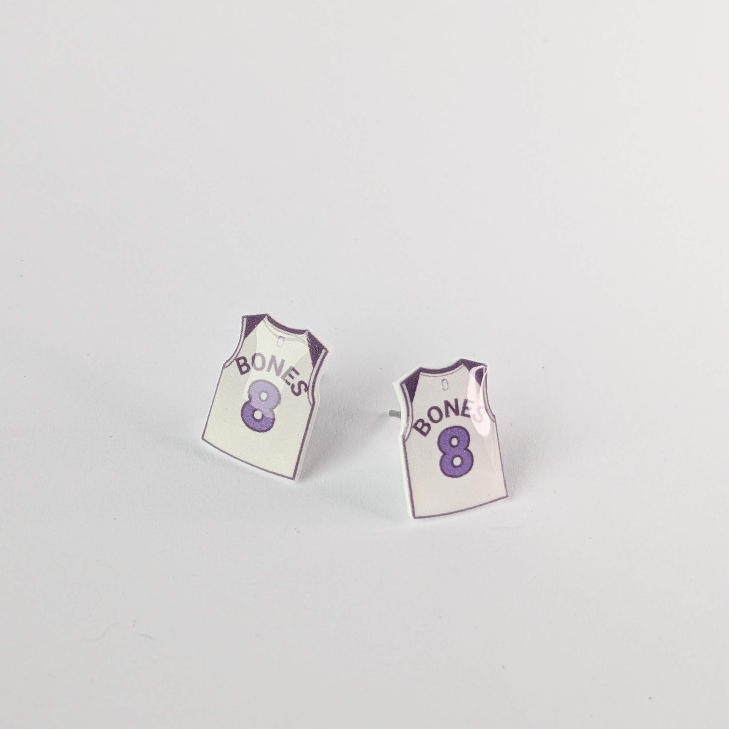 Pair of earrings shaped like miniature sports jerseys with 'Bones' and number '8' on a light gray background.