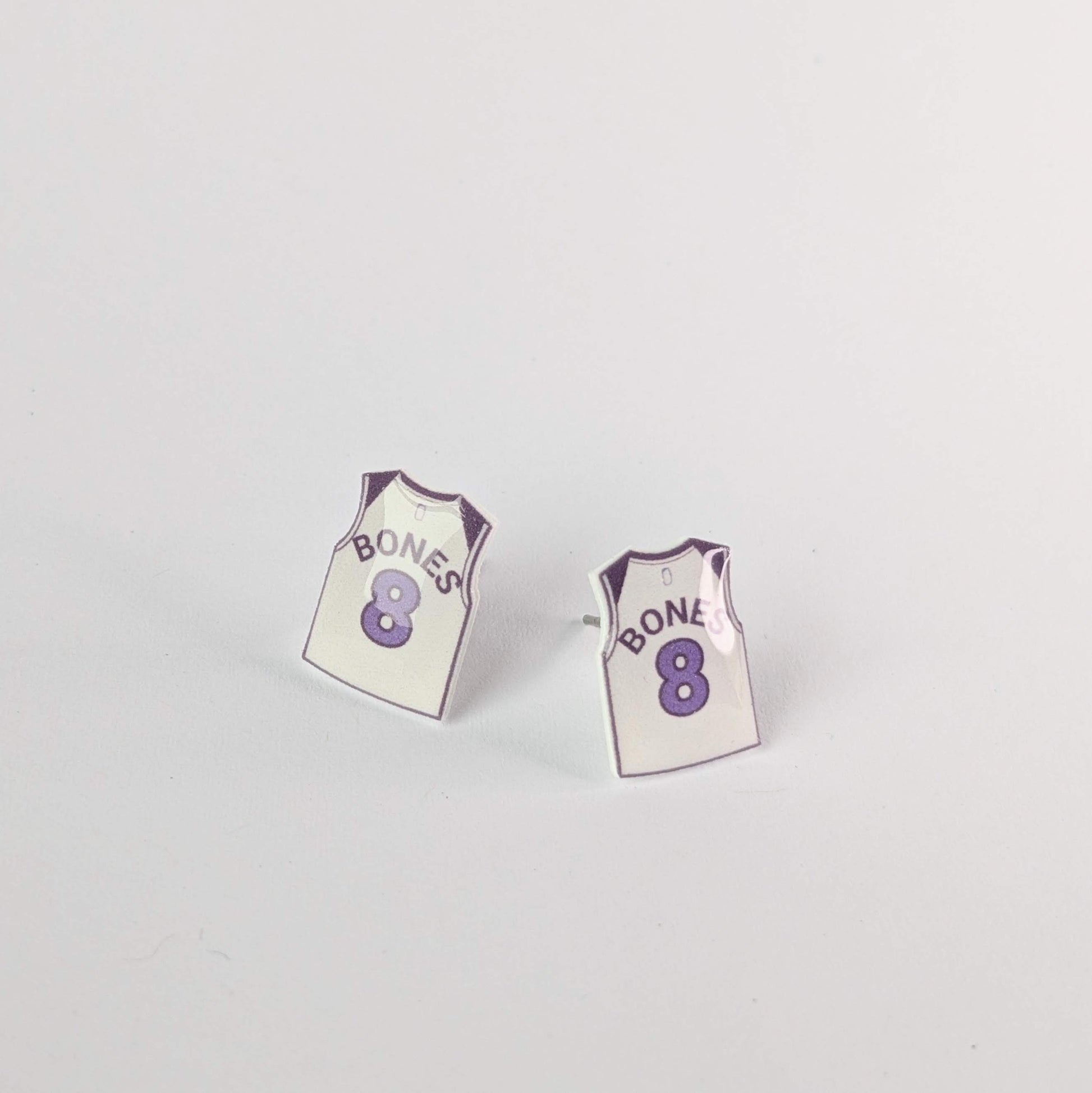 Pair of earrings shaped like miniature sports jerseys with 'Bones' and number '8' on a light gray background.