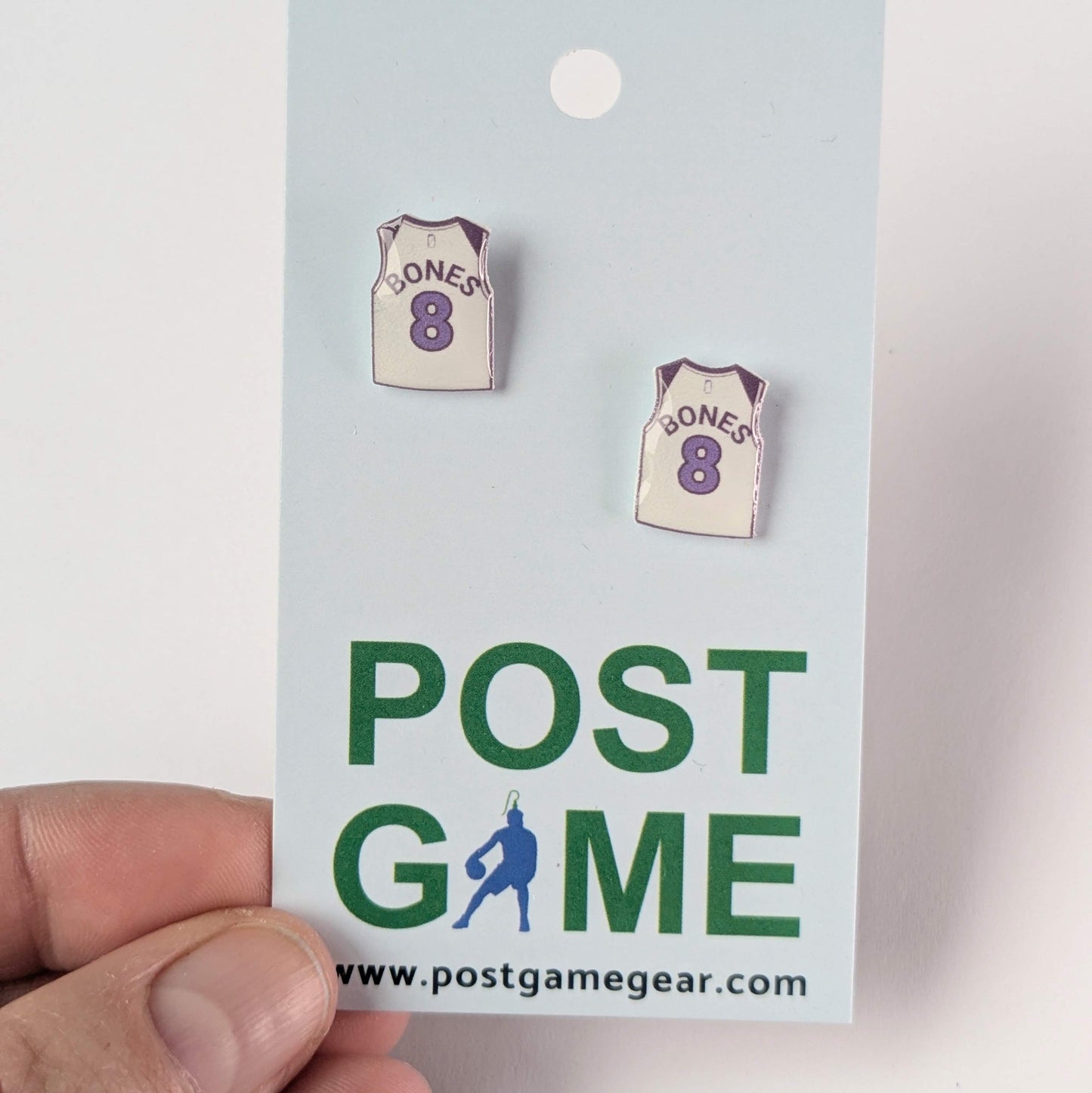 Pair of earrings shaped like basketball jerseys on a 'Post Game' branded card.