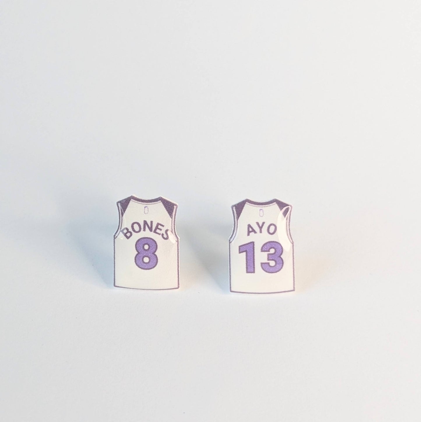 Two small basketball jersey earrings on a light gray background