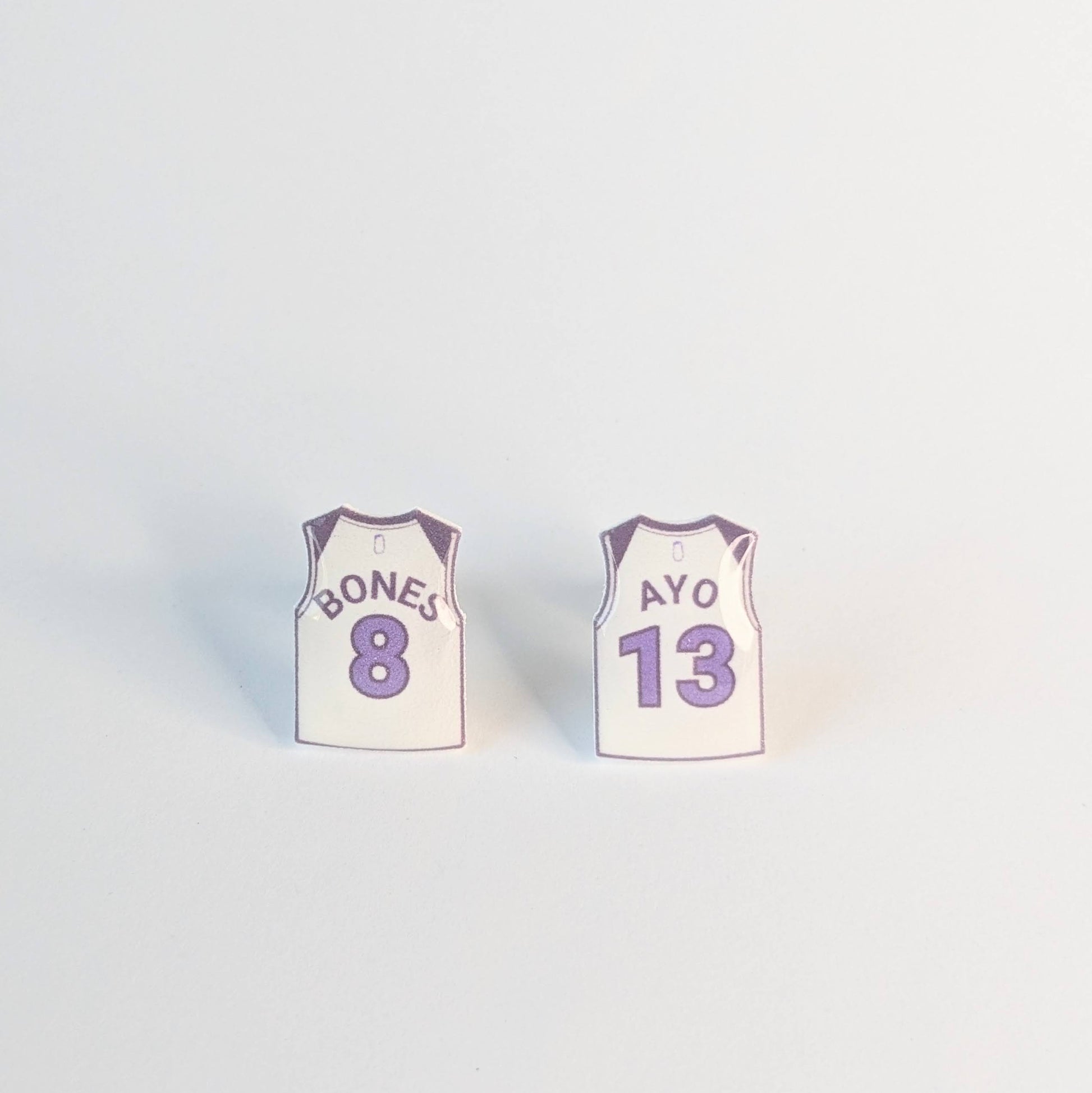 Two small basketball jersey earrings on a light gray background